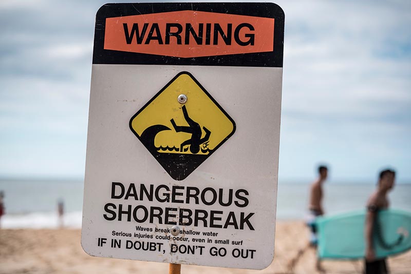 Safety officials post signs to alert beachgoers of hazardous conditions such as dangerous shorebreak. Valeria Venezia/Shutterstock.com