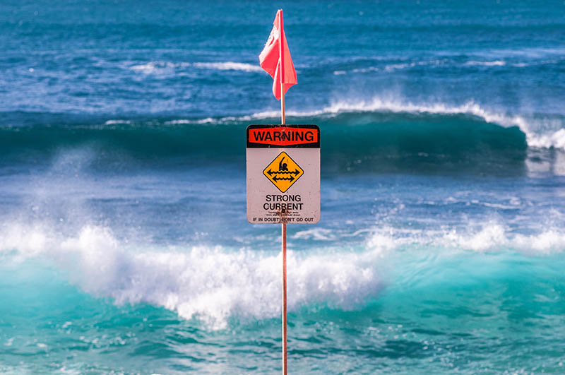A strong current sign warns beachgoers of dangerous conditions. Shamana/Iren Key/Shutterstock.com